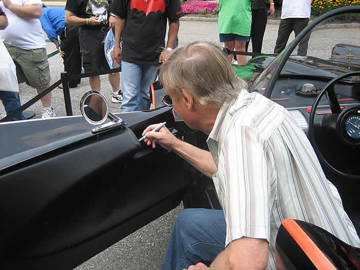 Adam West signs the "Rock Star" Batmobile.